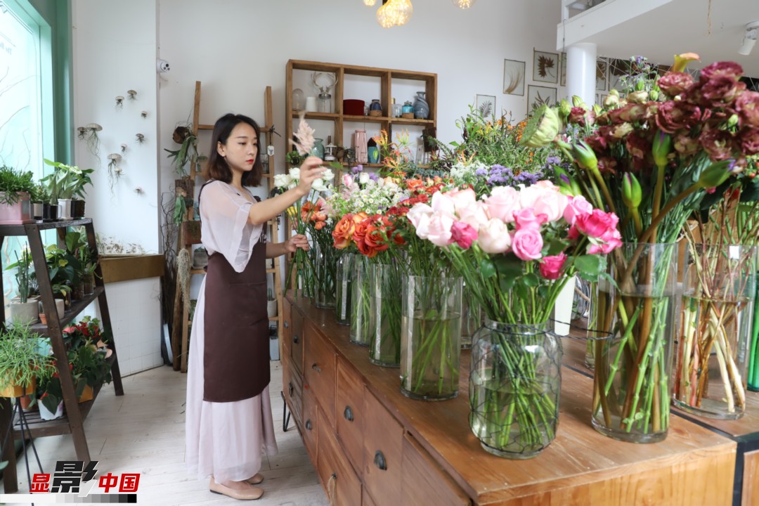 王黎媛是一名河南姑娘，在昆明念完大學(xué)后，就再也舍不下春城的藍(lán)天陽光、青山碧水，更舍不下這里的四時(shí)繁花，于是就干脆留了下來，成了一名媒體人。2017年的時(shí)候又毅然辭去工作，創(chuàng)業(yè)開起了花店，成了都市里的一名“花房姑娘”。圖為王黎媛在自己的花店中整理鮮花。新華網(wǎng) 周亞平/攝 念新洪/文